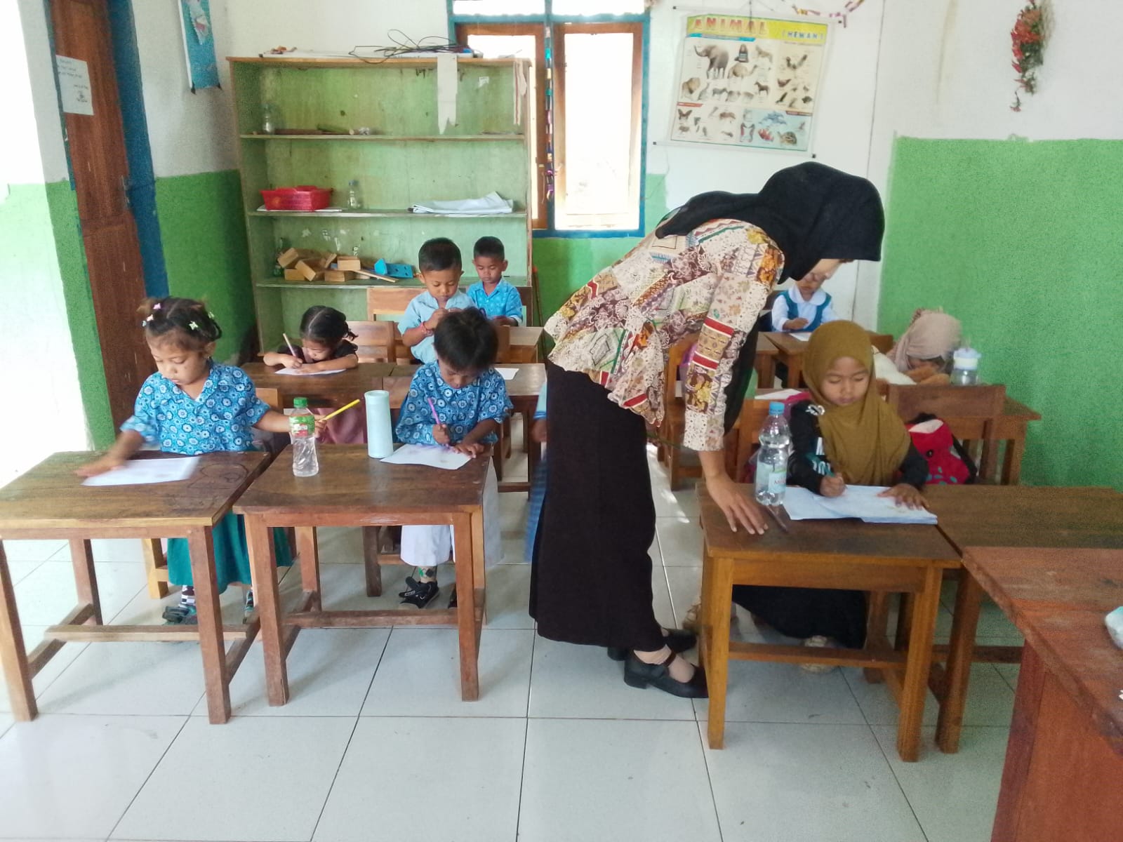 Anak-anak PAUD sedang mewarnai di dalam kelas dengan pendampingan guru.