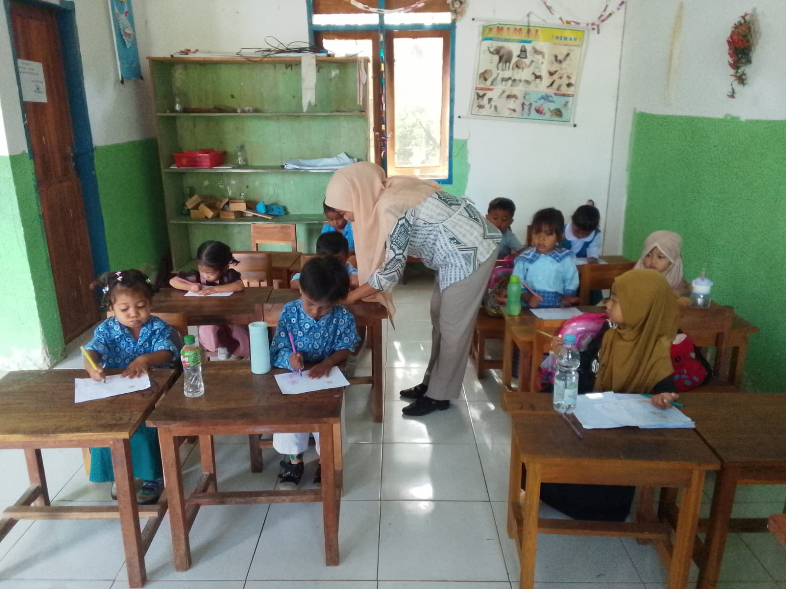 Guru mendampingi anak-anak saat mengikuti kegiatan mewarnai di kelas.
